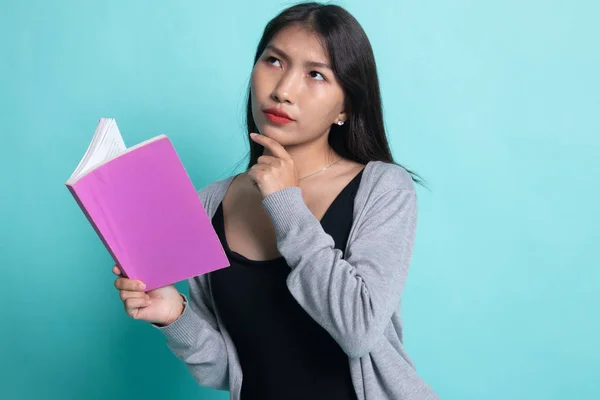 Junge asiatische Frau mit einem Buch denkt nach. — Stockfoto