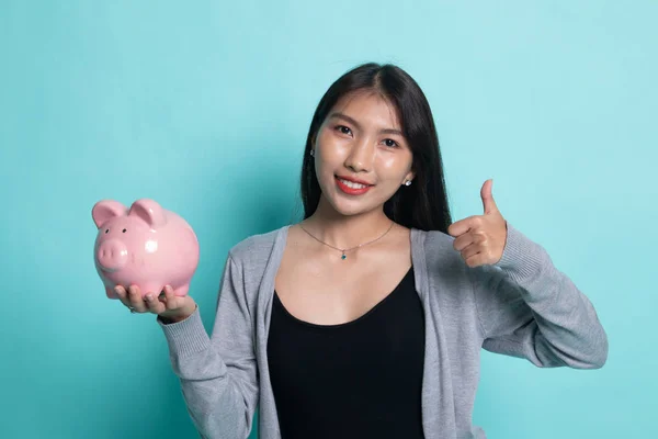 Azjatyckie kobiety kciuk w górę z pig monety bank. — Zdjęcie stockowe