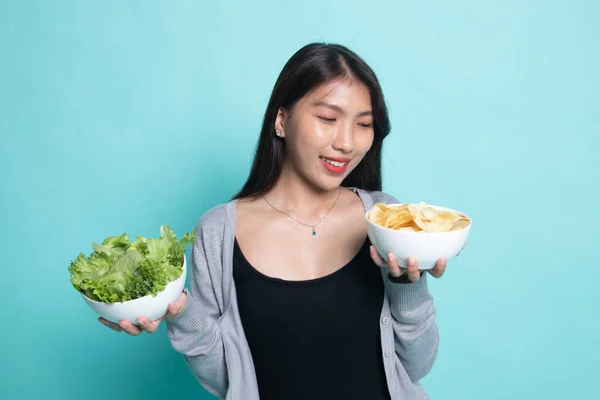 Ung asiatisk kvinna med potatischips och sallad. — Stockfoto