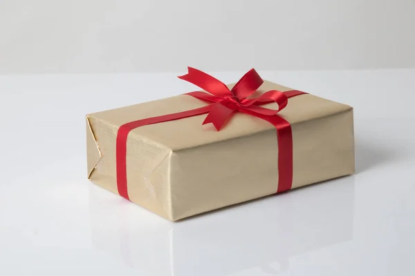 Golden gift box with red ribbon — Stock Photo, Image