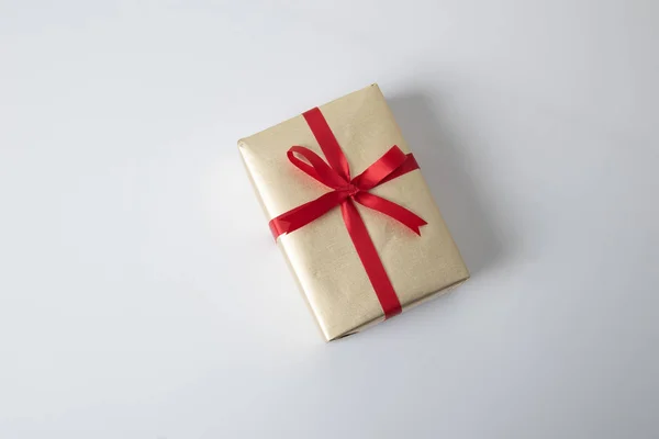 Gouden geschenkdoos met rood lint — Stockfoto