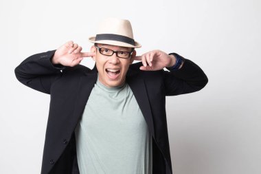 Yetişkin Asyalı adam beyaz arka planda parmaklarıyla iki kulağı da tıkamış.