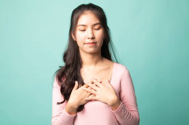 Sadık kadın gözlerini kapar ve ellerini kalbine yakın tutar. Cyan arka planda nezaketini gösterir.