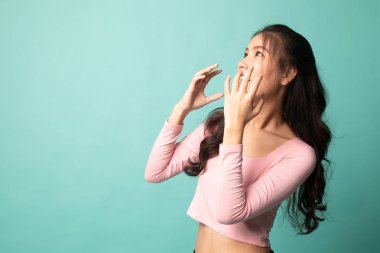 Güzel genç Asyalı kadın şok oldu ve Cyan arka planına baktı.