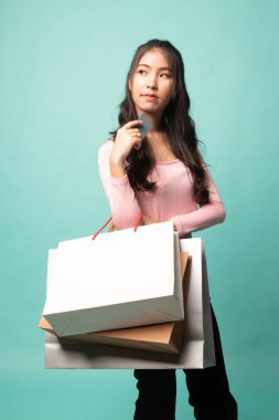 Alışveriş torbası ve Cyan arka planında boş kartı olan genç Asyalı kadın.