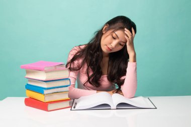 Bitkin düşmüş genç Asyalı kadın Cyan arka plan üzerine kitapları olan bir kitap okudu.