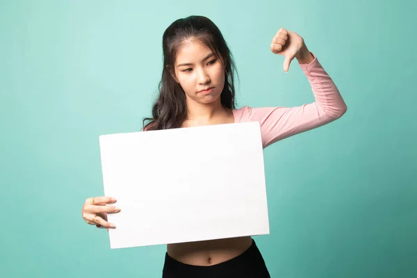 年轻的亚洲女人的大拇指垂下来 背景是青色的 上面有白色的空白标志 — 图库照片