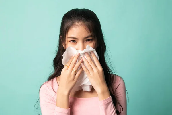 Young Asian woman got sick and flu on cyan background
