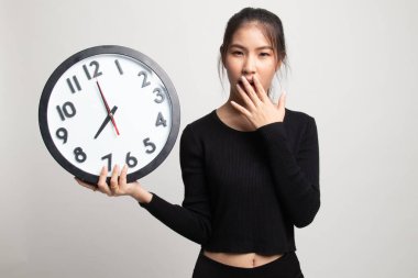 Beyaz arka plan üzerinde sabah bir saat ile uykulu genç Asyalı kadın