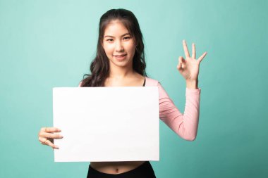 Genç Asyalı kadın Cyan arka planında beyaz boşluk işareti ile OK 'u gösteriyor.