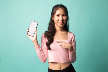 Genç Asyalı kadın Cyan arka planında cep telefonunu işaret ediyor
