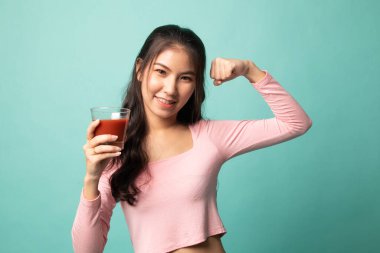 Cyan arka planında domates suyu olan güçlü sağlıklı Asyalı kadın.