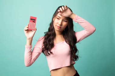 Asyalı kadının baş ağrısı var. Cyan arka planında hesap makinesi var.