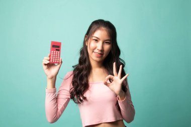 Asyalı kadın Cyan arka planında hesap makinesiyle OK 'u göster
