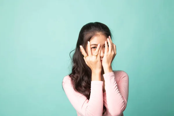 美丽的年轻亚洲女人透过手指窥视着青色的背景 — 图库照片