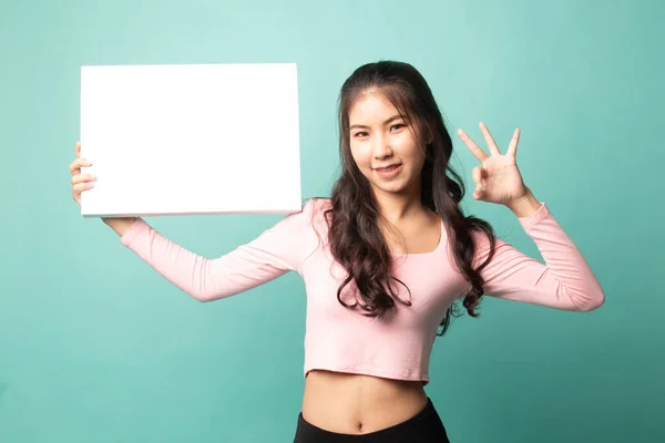 Молодая Азиатка Показывает Белым Пустым Знаком Голубом Фоне — стоковое фото