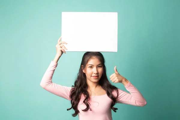 年轻的亚洲女人的大拇指上有蓝色背景的白色空白标志 — 图库照片
