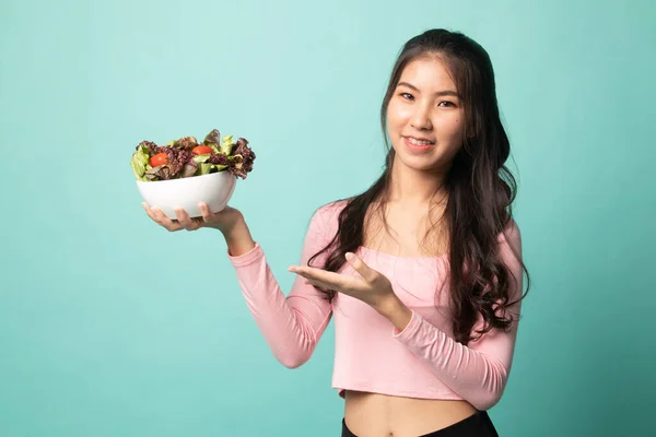 Healthy Asian woman with salad on cyan background