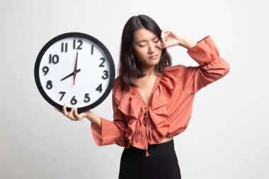 Beyaz arka plan üzerinde sabah bir saat ile uykulu genç Asyalı kadın