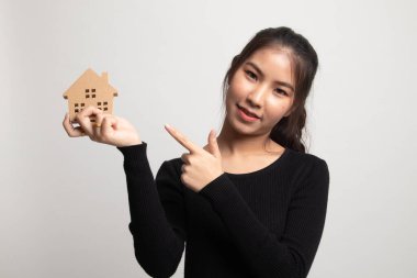 Beyaz arka planda ev modeli olan mutlu genç Asyalı kadın.