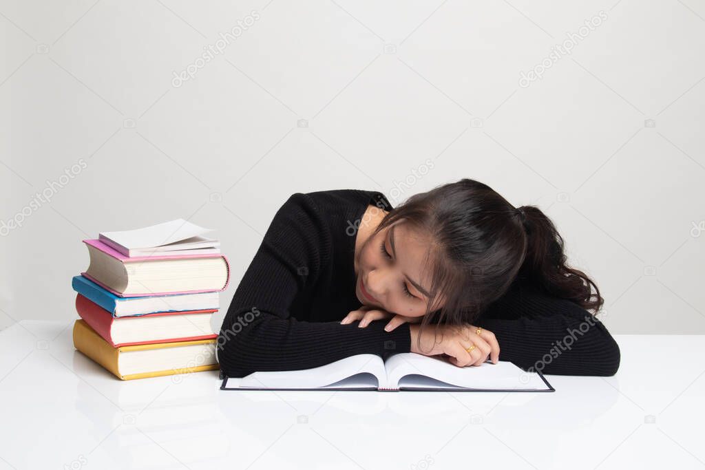 Exhausted Young Asian woman sleep with books on table on white background