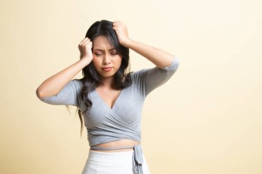 Genç Asyalı kadın hastalandı ve bej arka planda baş ağrısı başladı.