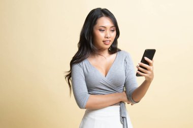 Bej arka planda cep telefonu olan genç Asyalı kadın.