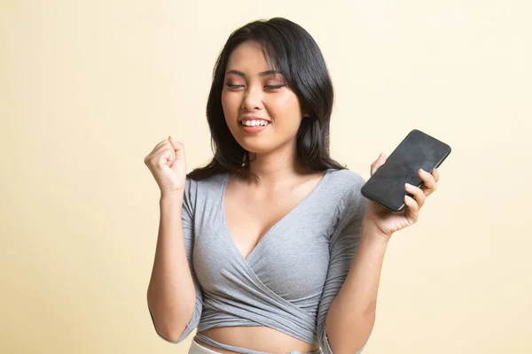 Happy Young Asian woman with mobile phone   on beige background