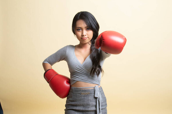 Молодая азиатка в красных боксёрских перчатках на бежевом фоне
