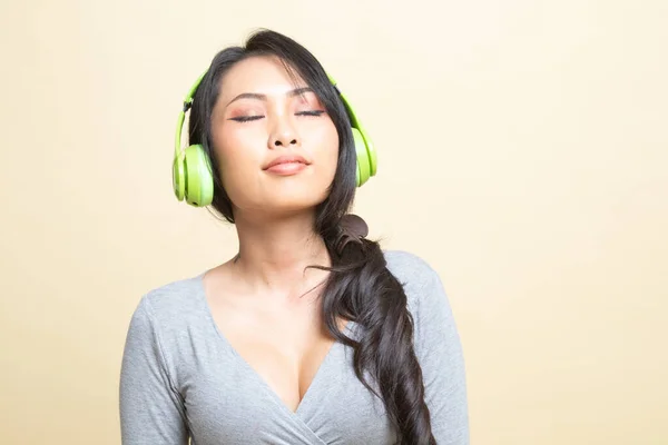 漂亮的亚洲女孩 带着米色背景的耳机听音乐 — 图库照片