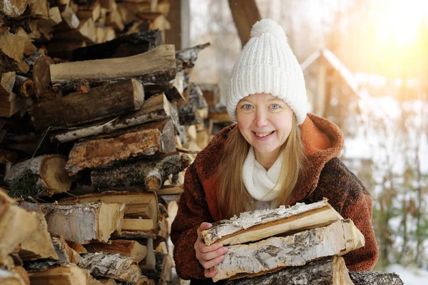 Woman gathering wood outside winter cabin.