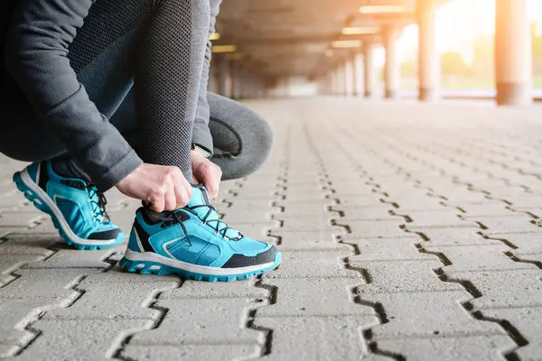 Female runner tying shoe lace in a urban area.