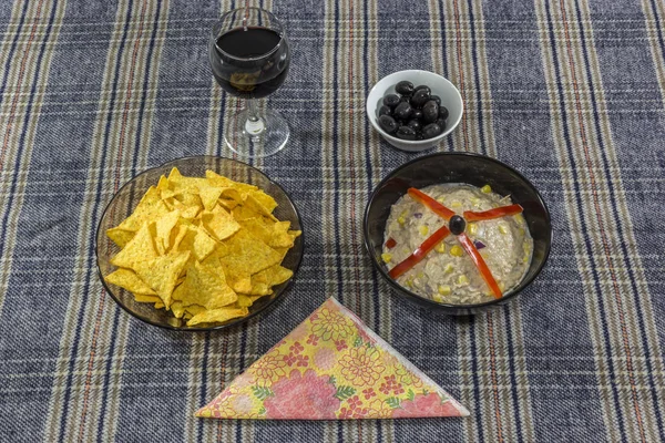 Bowl of tuna salad, tortilla chips, olives and glass of red wine — Stock Photo, Image