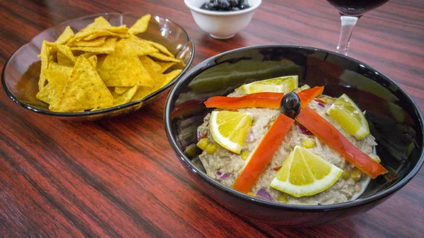 Ciotola di insalata di tonno, tortilla chips, olive e bicchiere di vino rosso — Foto Stock