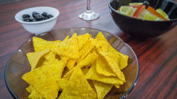 Schüssel mit Thunfischsalat, Tortilla-Chips, Oliven und einem Glas Rotwein — Stockfoto