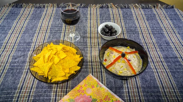 Bowl of tuna salad, tortilla chips, olives and glass of red wine — Stock Photo, Image