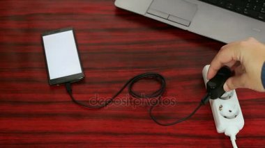 Telefon elektrik soketine ve güç uzatma kablosuna bir kablo ve adaptör aracılığıyla bağlı.