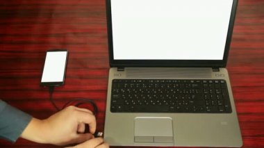 Bir dizüstü bilgisayarda bir uzatma kablosu kablo ve adaptör aracılığıyla telefon bağlı.