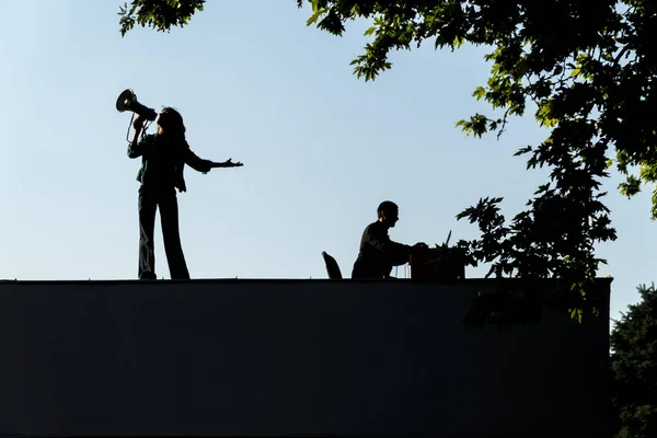 Girl singing with a loudspeaker on a roof — Stock Photo, Image
