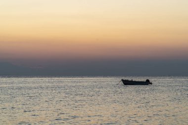 Gün batımında denizin ortasında bir tekne.