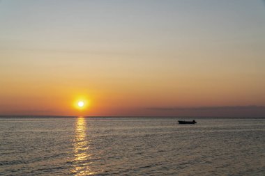 Gün batımında denizin ortasında bir tekne.