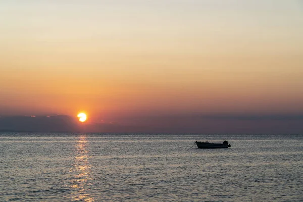 Gün batımında denizin ortasında bir tekne. — Stok fotoğraf