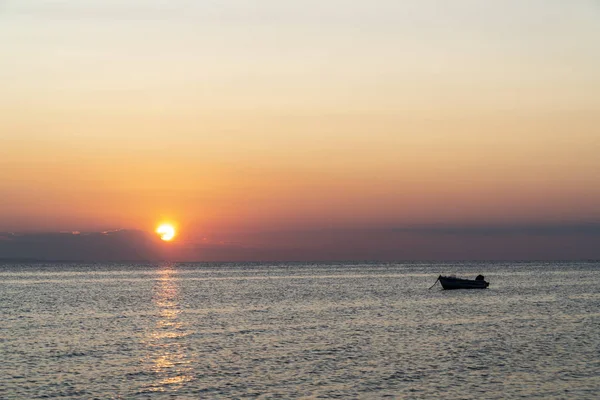 Gün batımında denizin ortasında bir tekne. — Stok fotoğraf