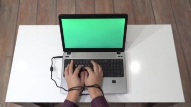 Modern kölelik kavramı. Bir adamın elleri dizüstü bilgisayarda yazarken ve şarj kablosuyla bağlanmışken..