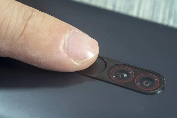 Macro shot of an index finger touching a fingerprint reader on a smartphone