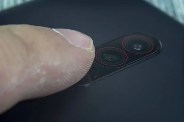 Macro shot of an index finger touching a fingerprint reader on a smartphone