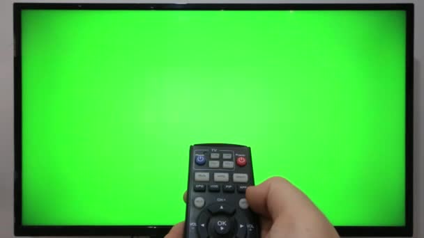 Направляя Пульт Телевизора Нажимая Кнопки Перед Телевизором Зеленым Экраном — стоковое видео