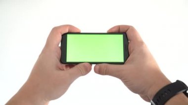 Beyaz arkaplanda yatay pozisyonda boş ekranlı bir akıllı telefonu tutmak. Bir video konsepti izlemek.