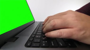 Diz üstü bilgisayarda yazan bir adamın beyaz arka planda düşük açılı görüntüsü.
