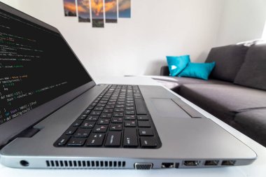 Uzaktan kumanda merkezi. Evdeki bir dizüstü bilgisayarda kod yazan bir programcının düşük açılı görüntüsü.
